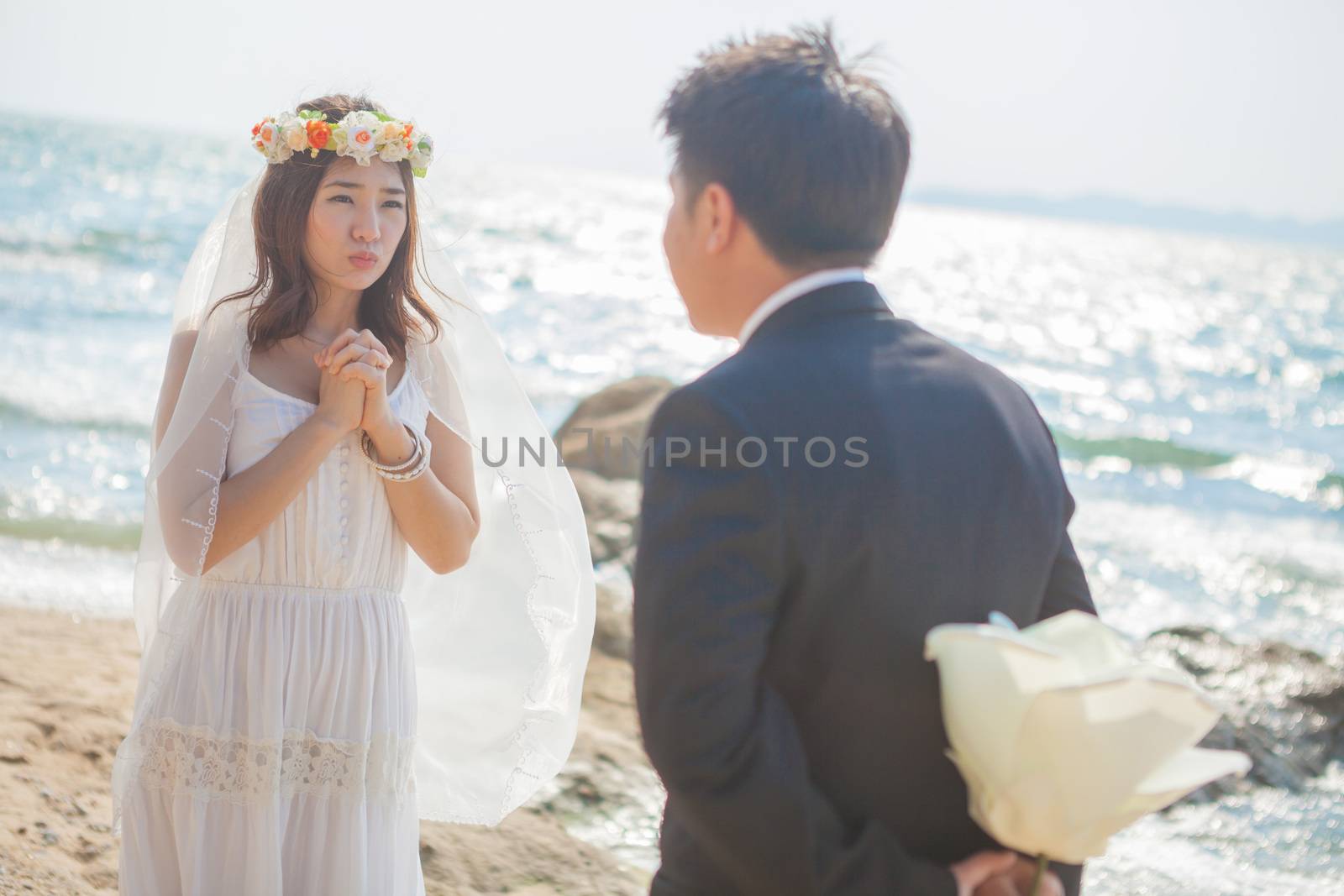 Beautiful asian couple on the beach in wedding dress