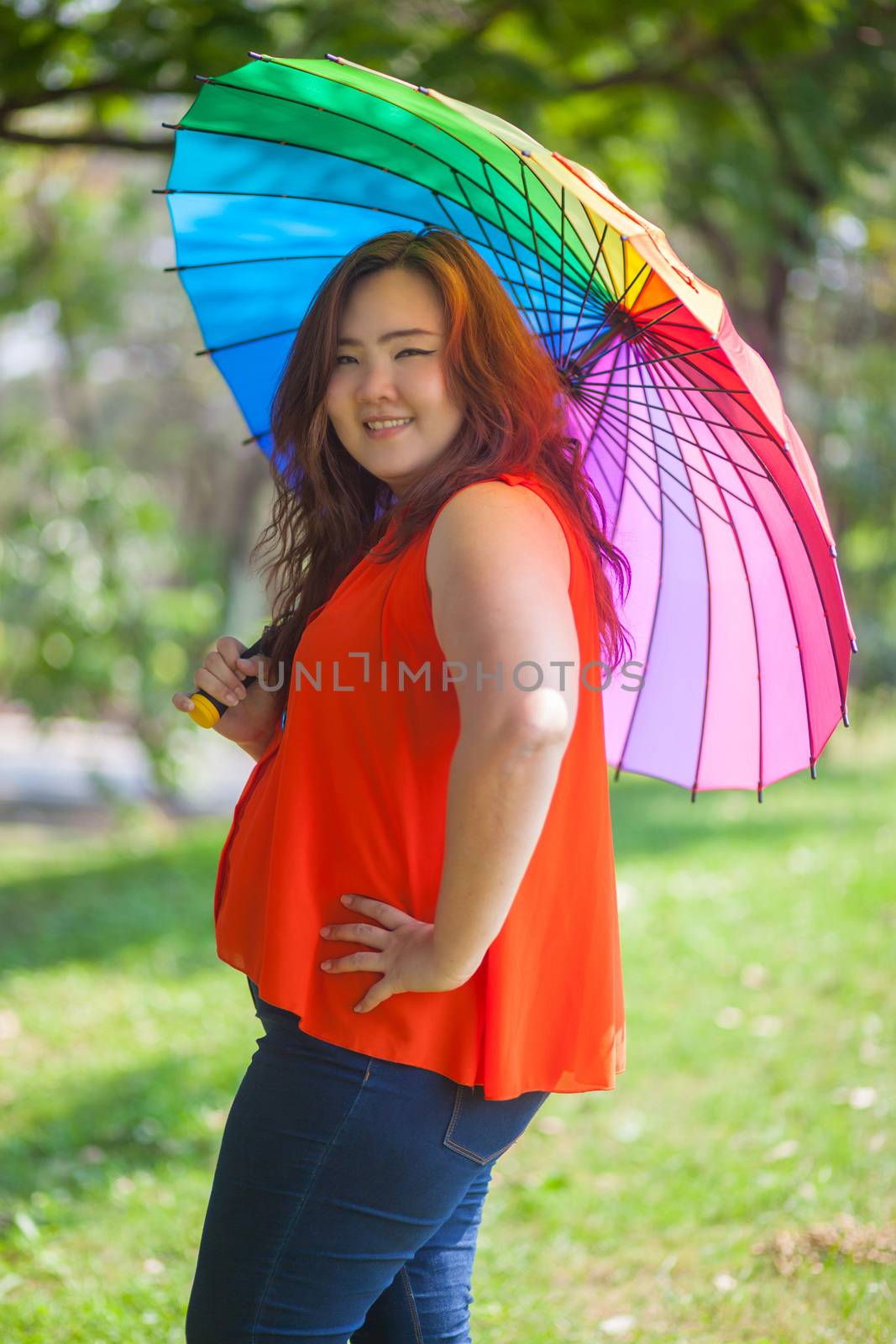 Happy fatty asian woman with umbrella outdoor in a park