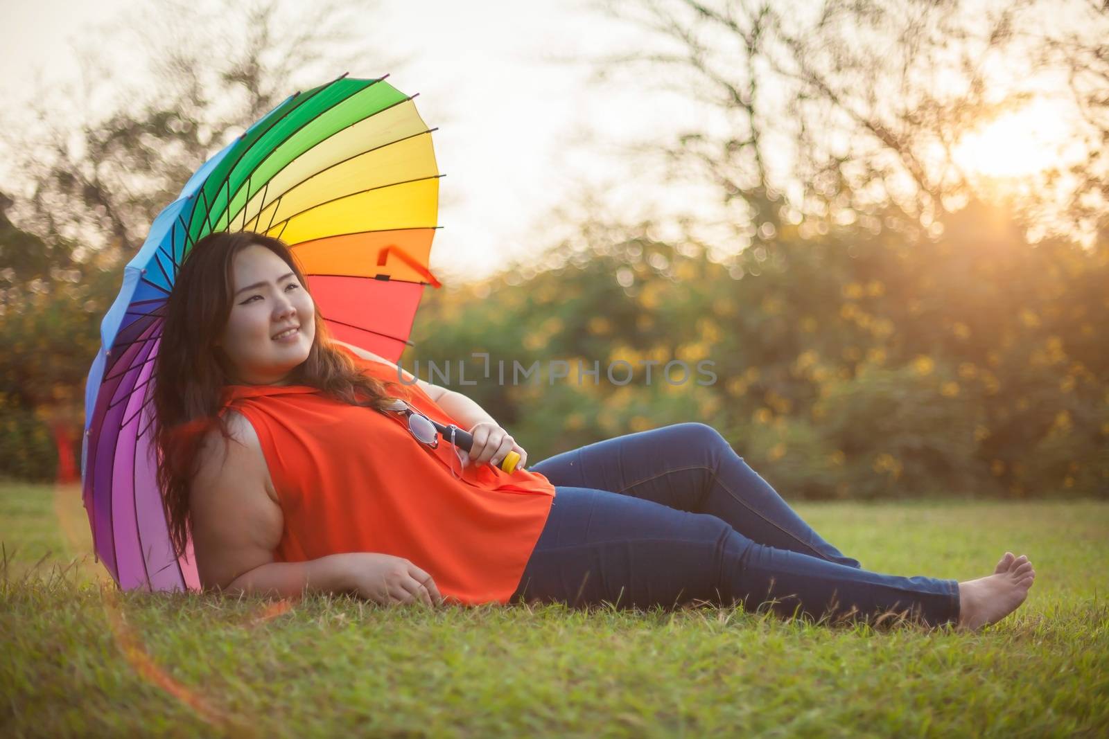 Happy fatty asian woman with umbrella outdoor in a park