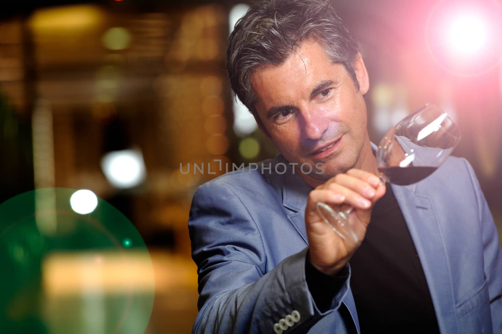 Winegrower in wine-cellar holding glass of wine