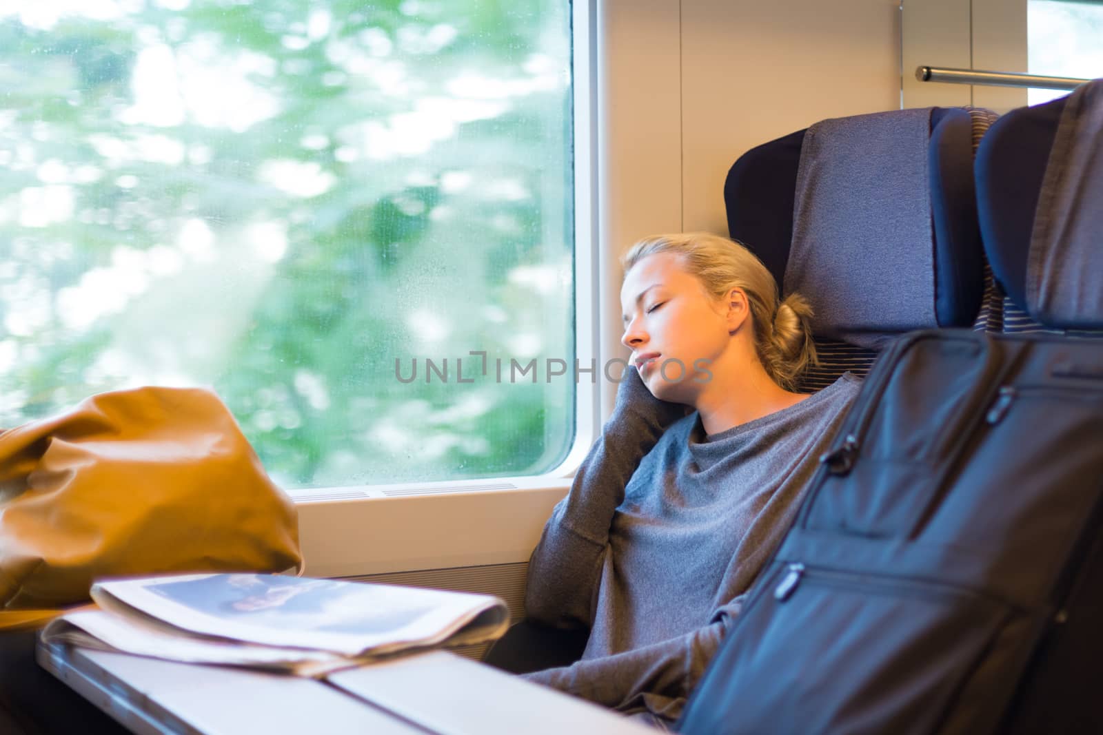 Blonde casual caucasian lady napping while traveling by train.
