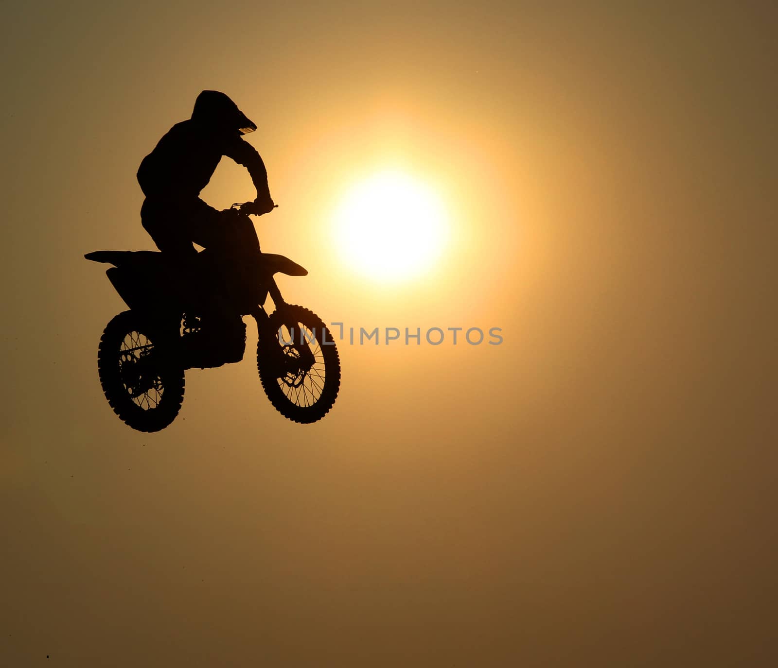 Motorcycle jumps in the air with sunset