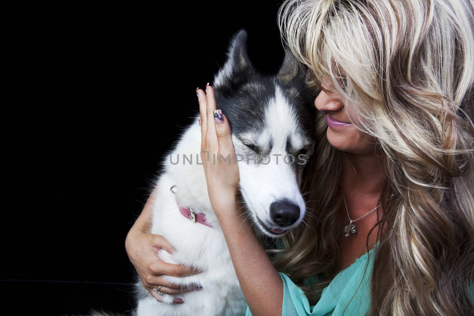 An affectionate dog owner hugging her American Husky dog. 