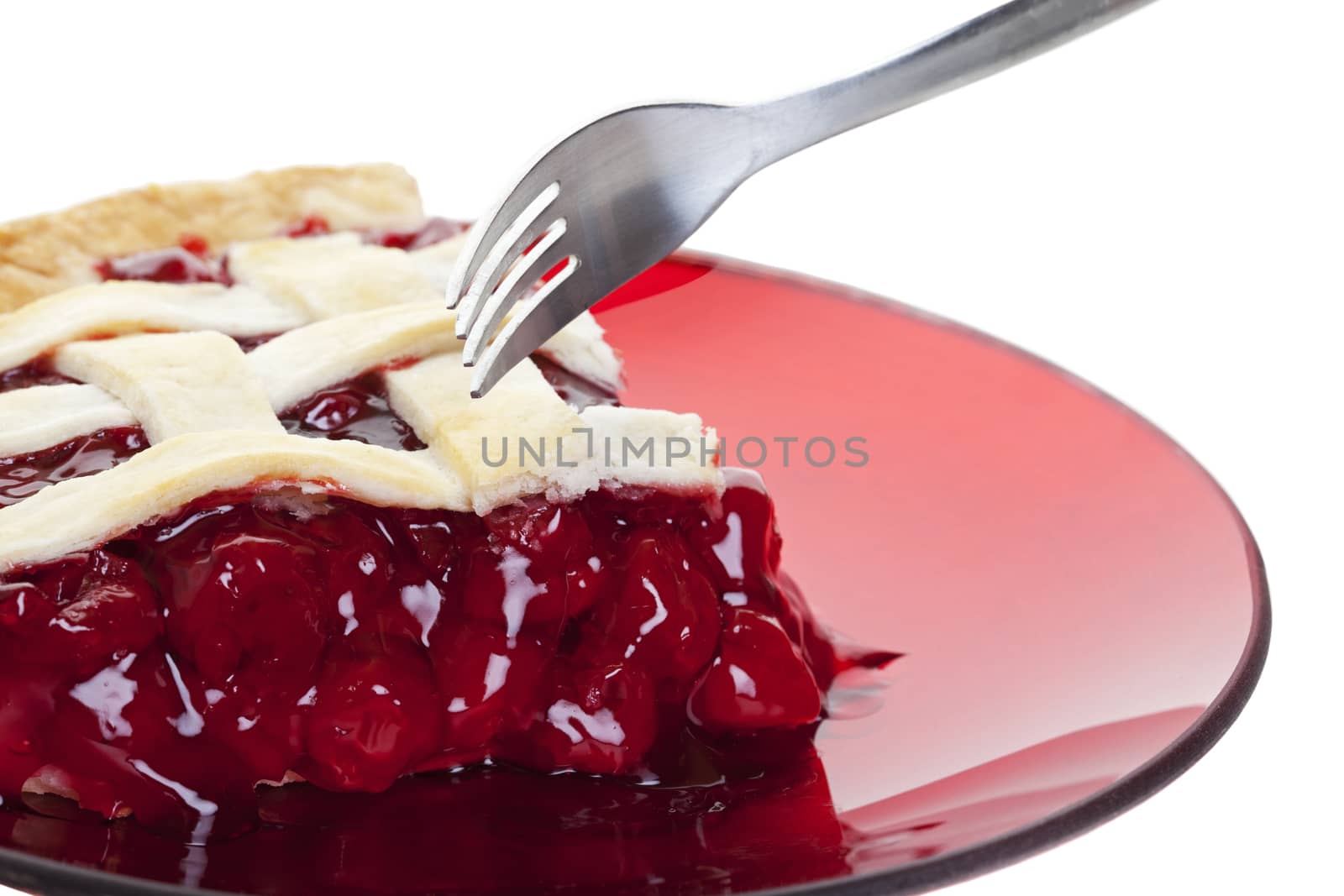 A serving of cherry pie about to be cut into with a fork.  Shot on white background.