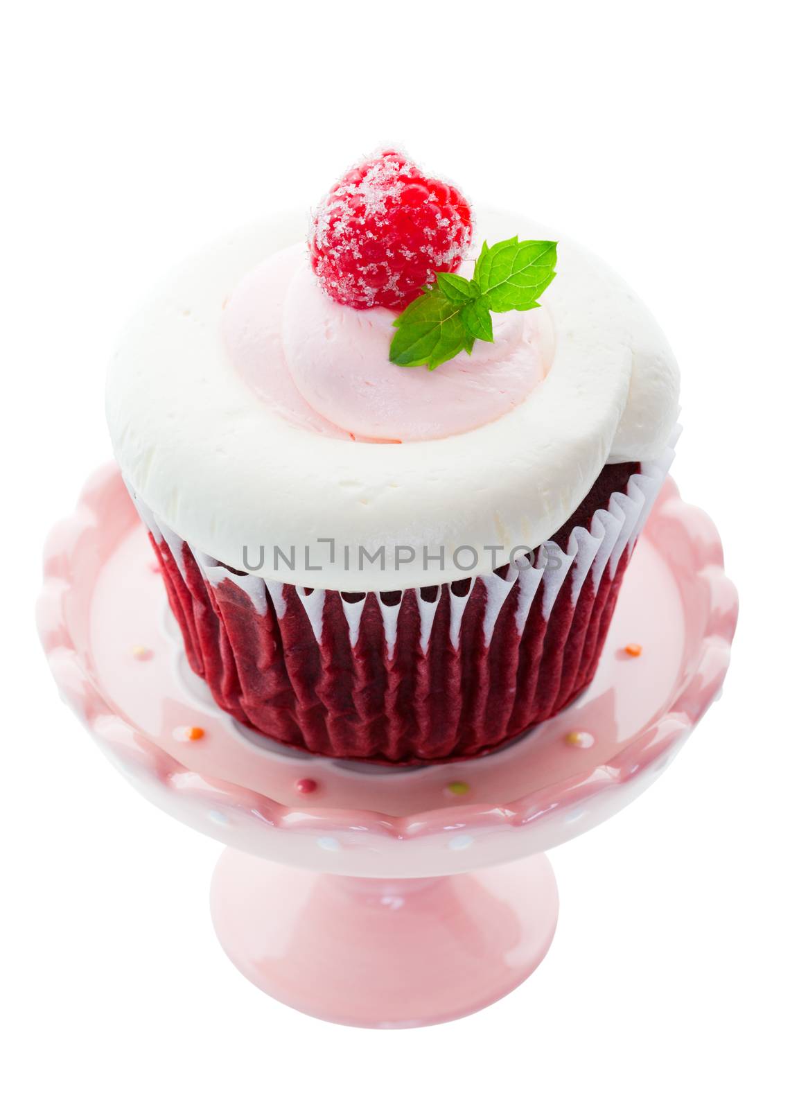 Red Velvet cupcake with pink and white whipped cream cheese icing, and a sugared raspberry with a sprig of mint as garnish.  Served on a mini cupcake pedestal.  Shot on white background.