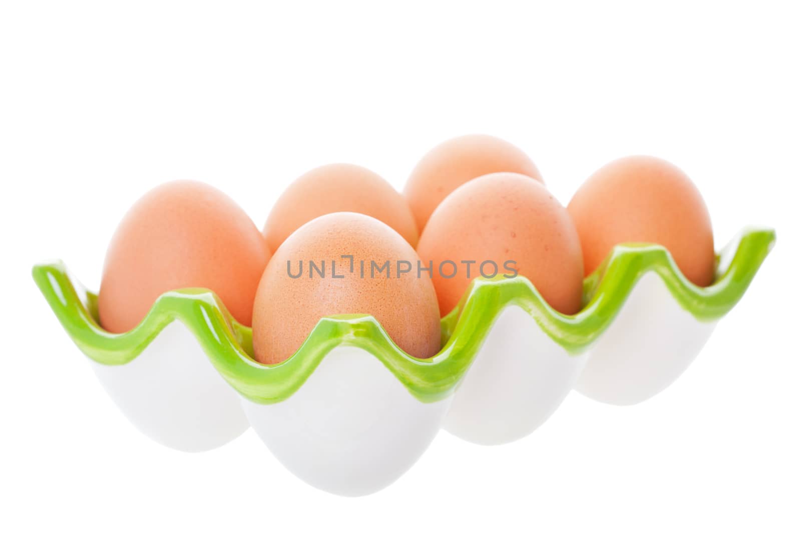 Half a dozen brown eggs in a green ceramic egg tray.  Shot on white background.