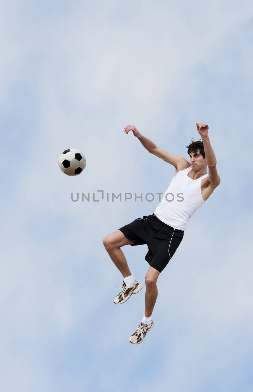 A soccer player jumps up into the air and hits the ball with his knee.