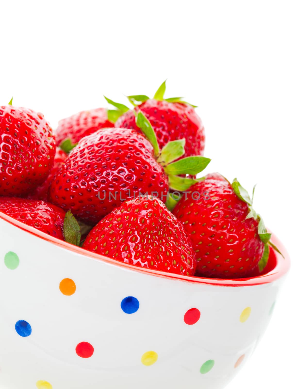 Ripe, juicy, freshly washed, strawberries heaped in a summer fun, polka-dot bowl.  Shot on white background.