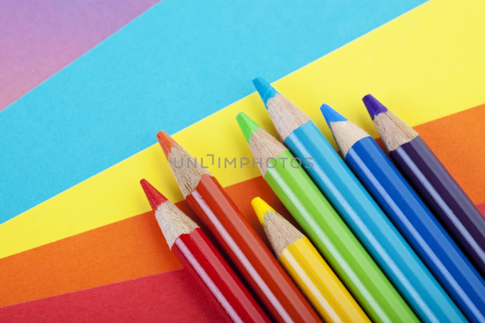 A rainbow of pencil crayons and scrapbooking papers ready for creative use.