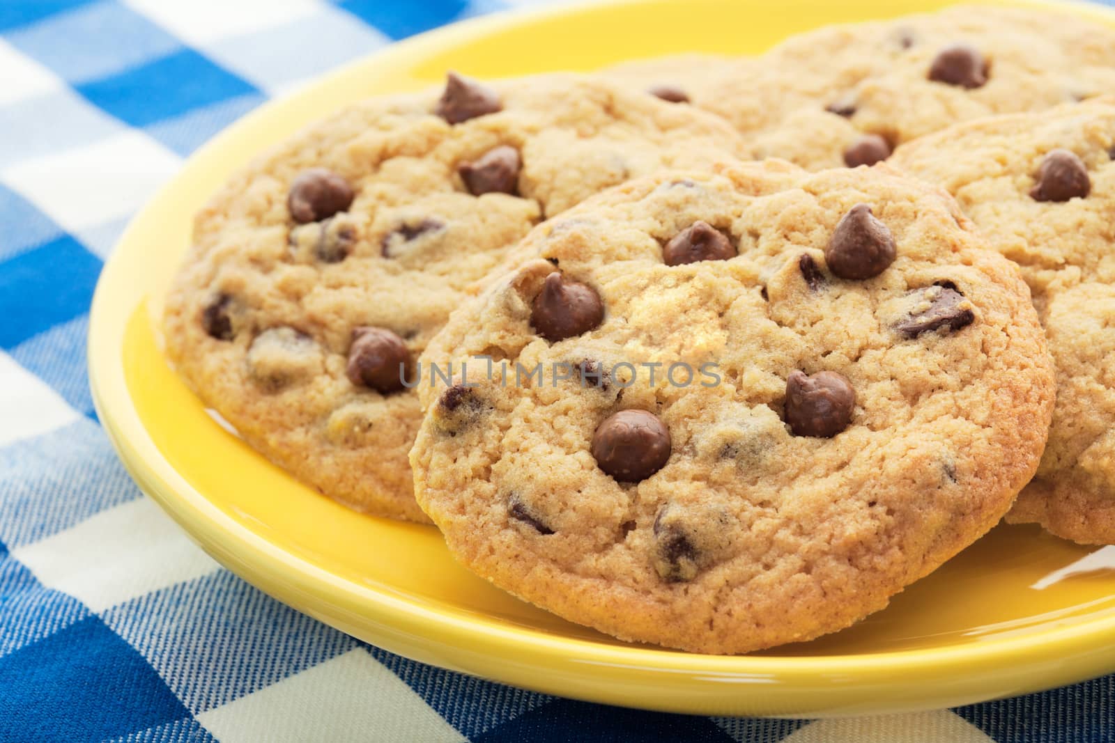 Homemade, chocolate chip cookies, like Mom used to make, served on a yellow plate.  Shallow depth of field.
