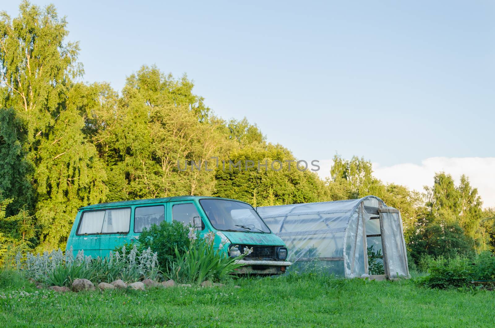 old mini bus parked next to the village greenhouse in the yard