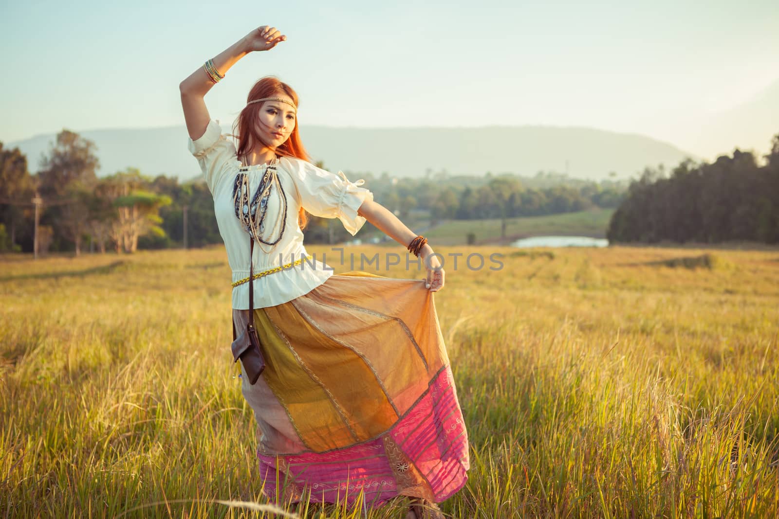 Hippie woman posing in golden field on sunset