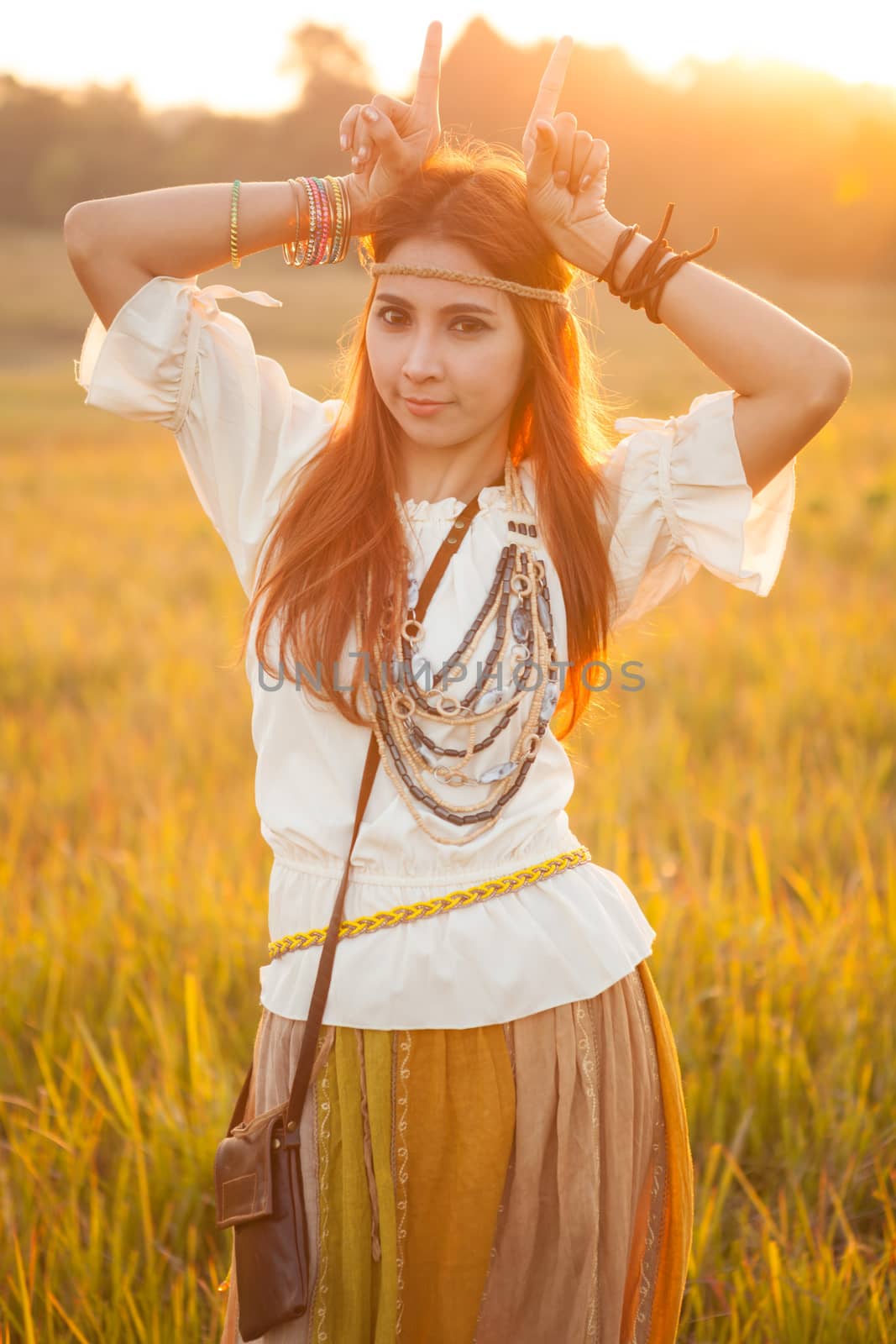 Hippie woman posing in golden field on sunset