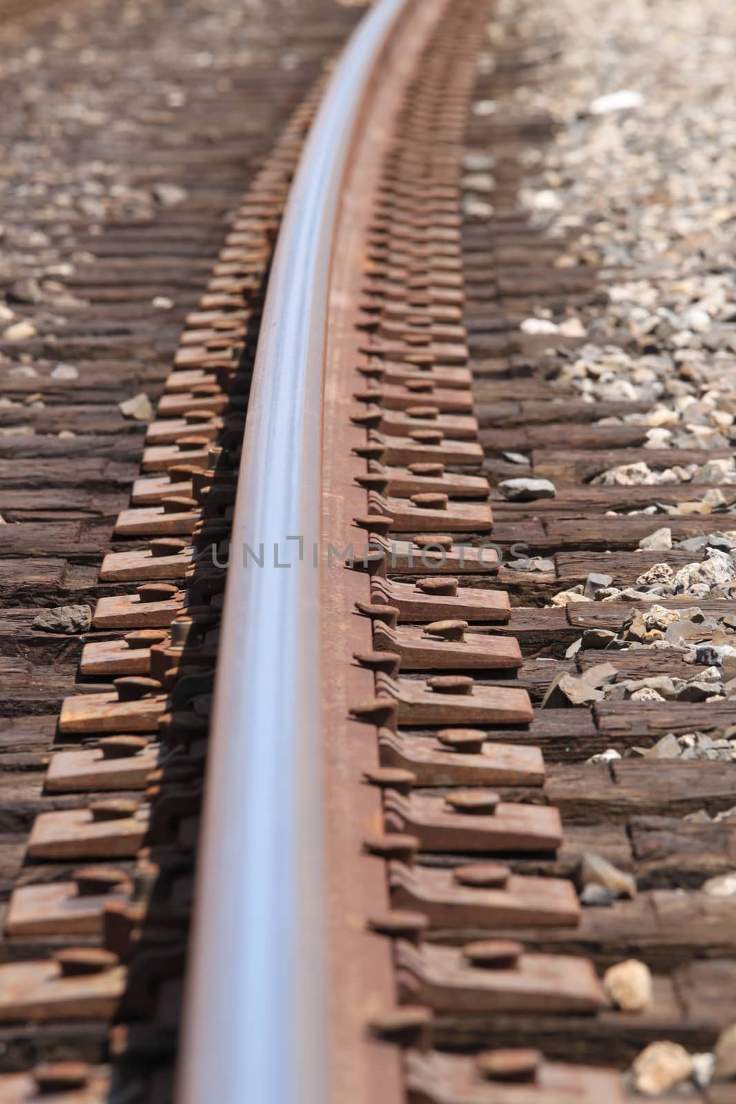 One single train track in gravel with a curve.