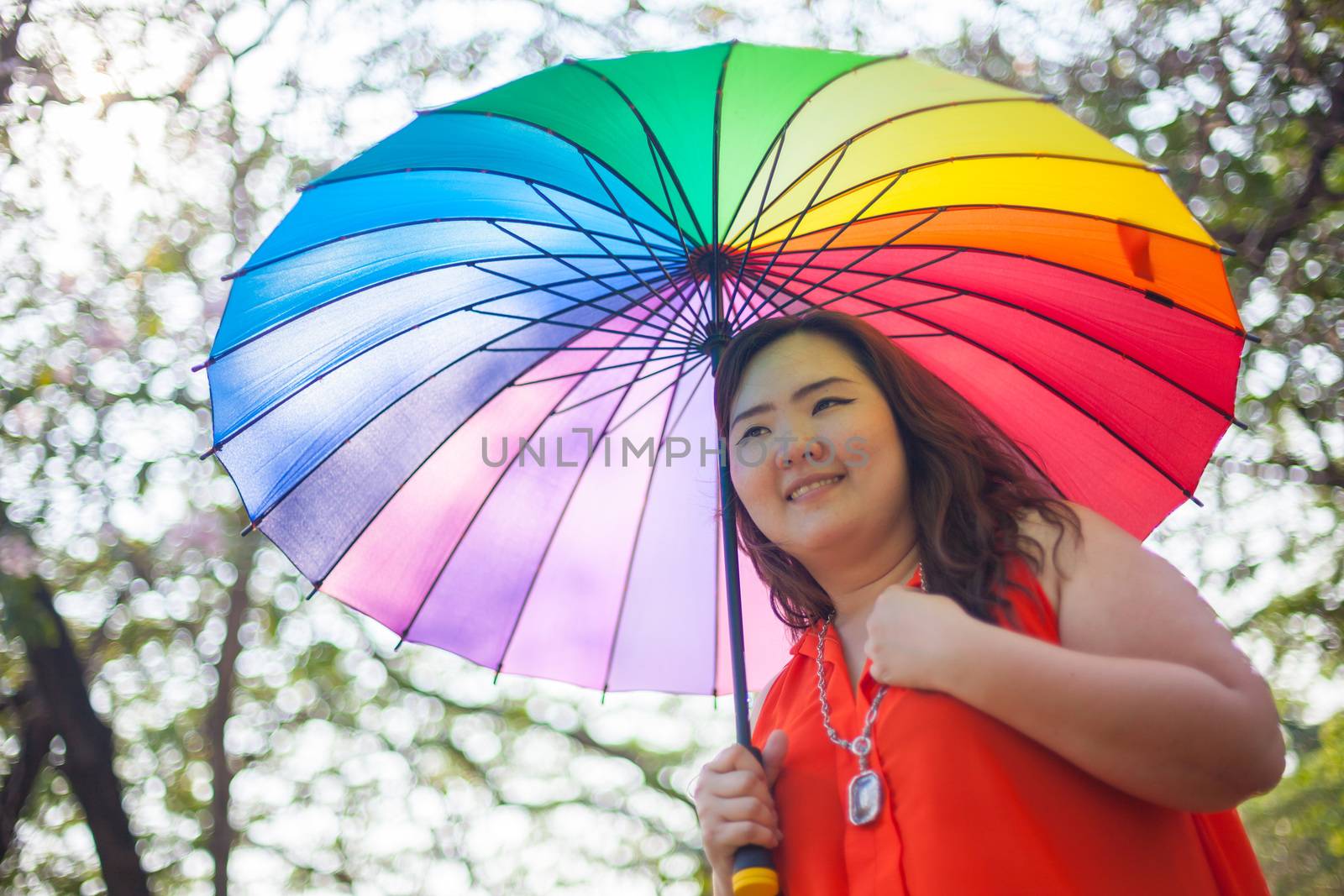 Happy fatty asian woman with umbrella outdoor in a park