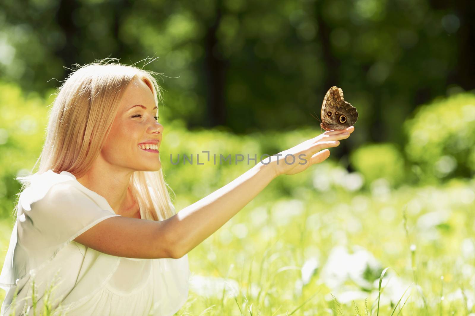 Beautiful young happy Woman playing with butterfly outdoors