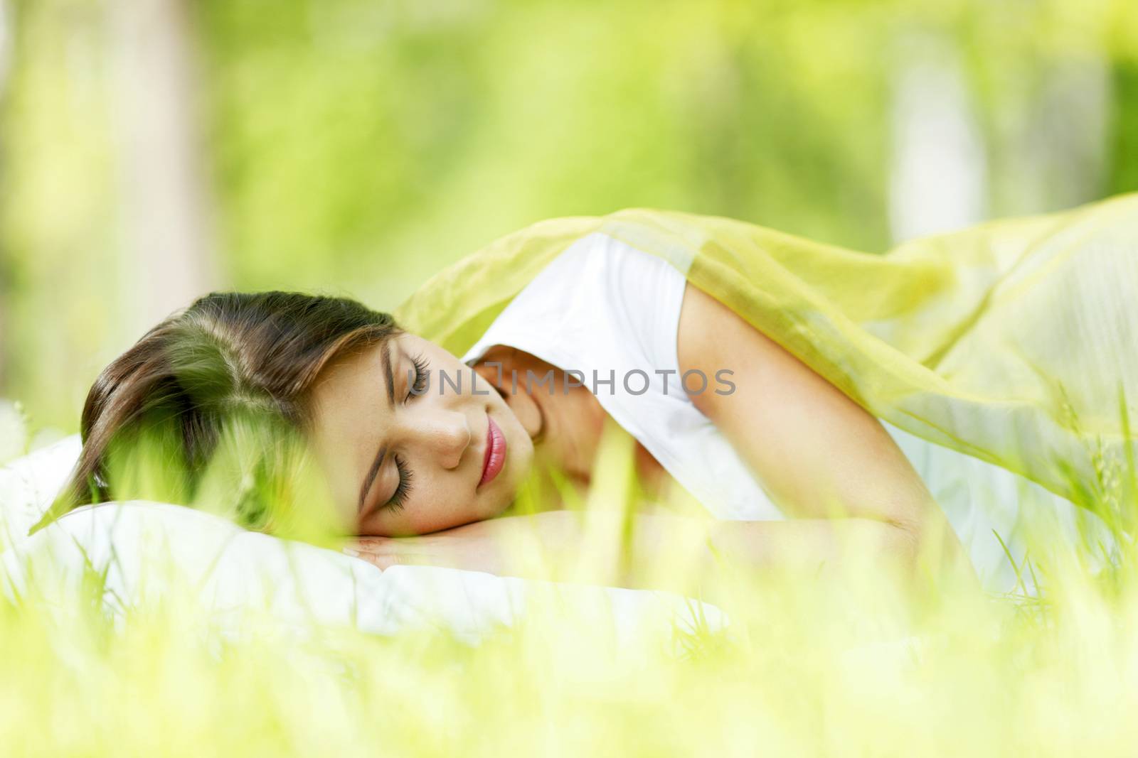 Beautiful young woman sleeping on grass outdoors