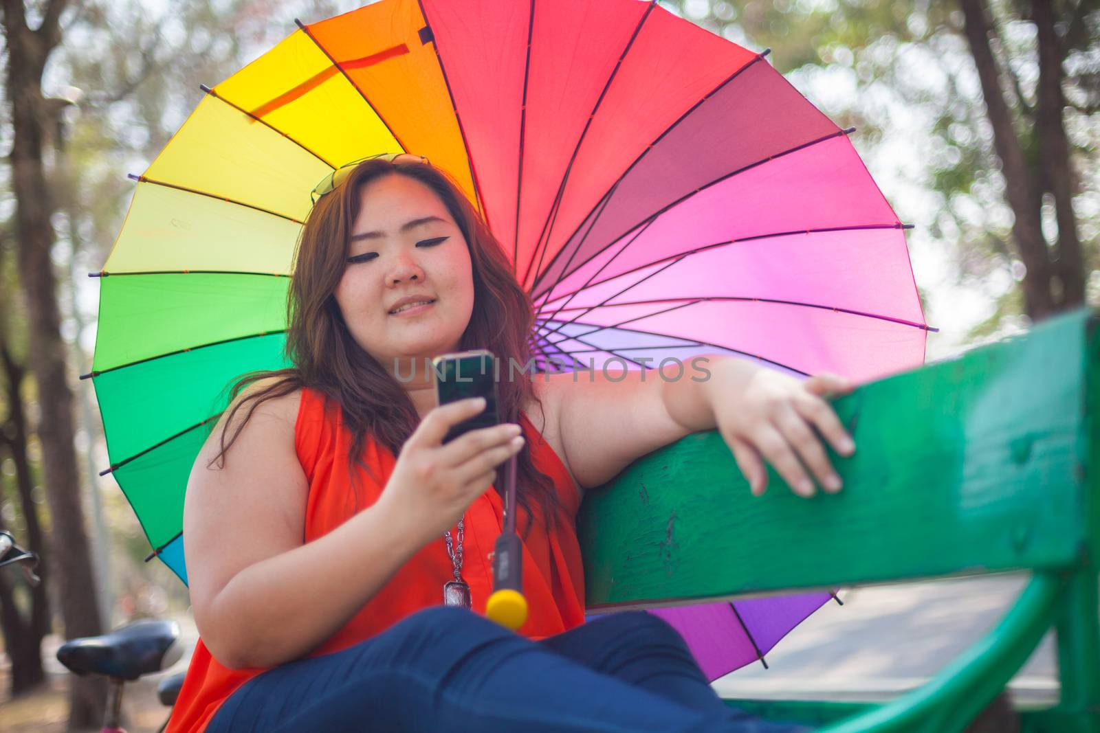 Happy fatty asian woman using mobile phone outdoor in a park