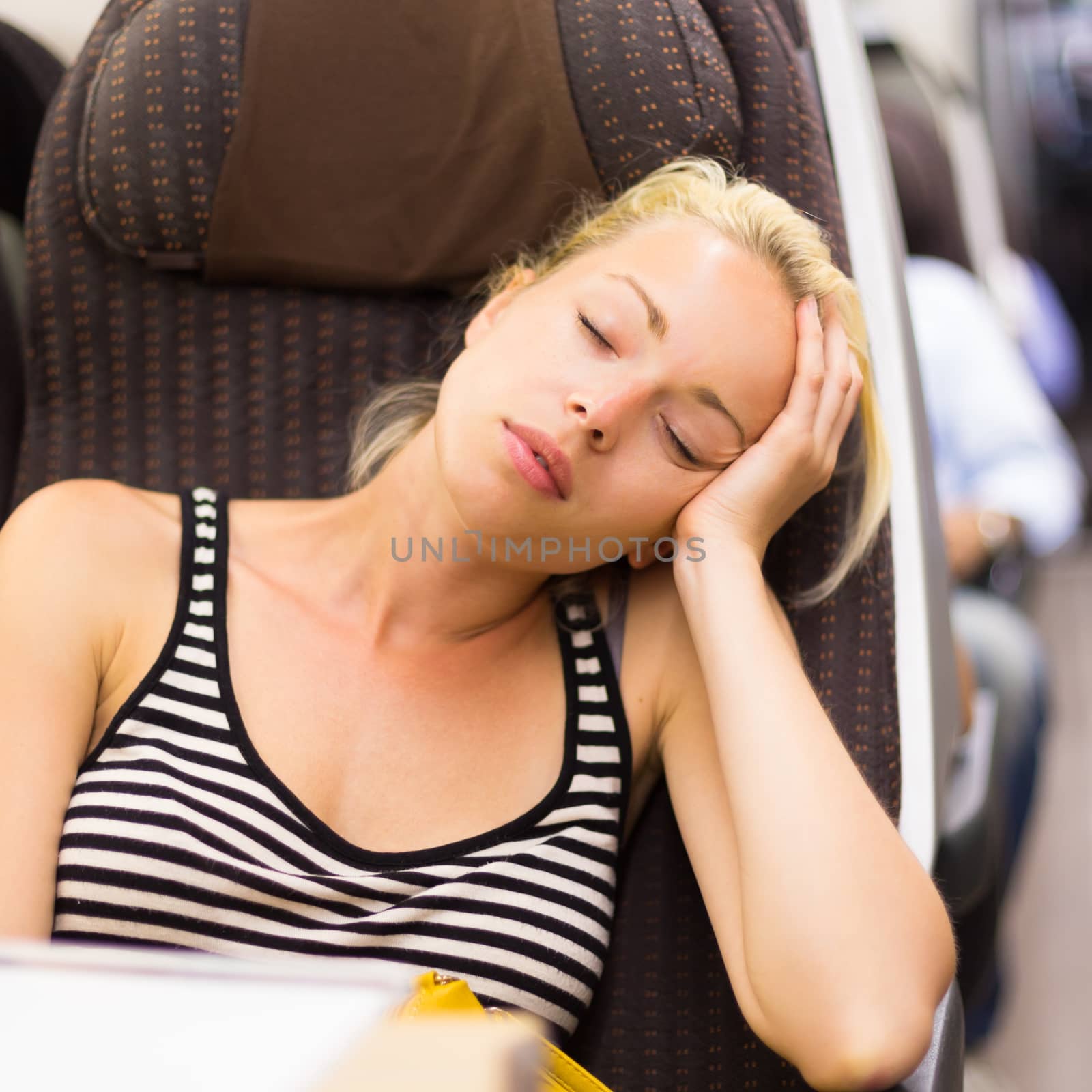 Blonde casual caucasian lady napping while traveling by train.