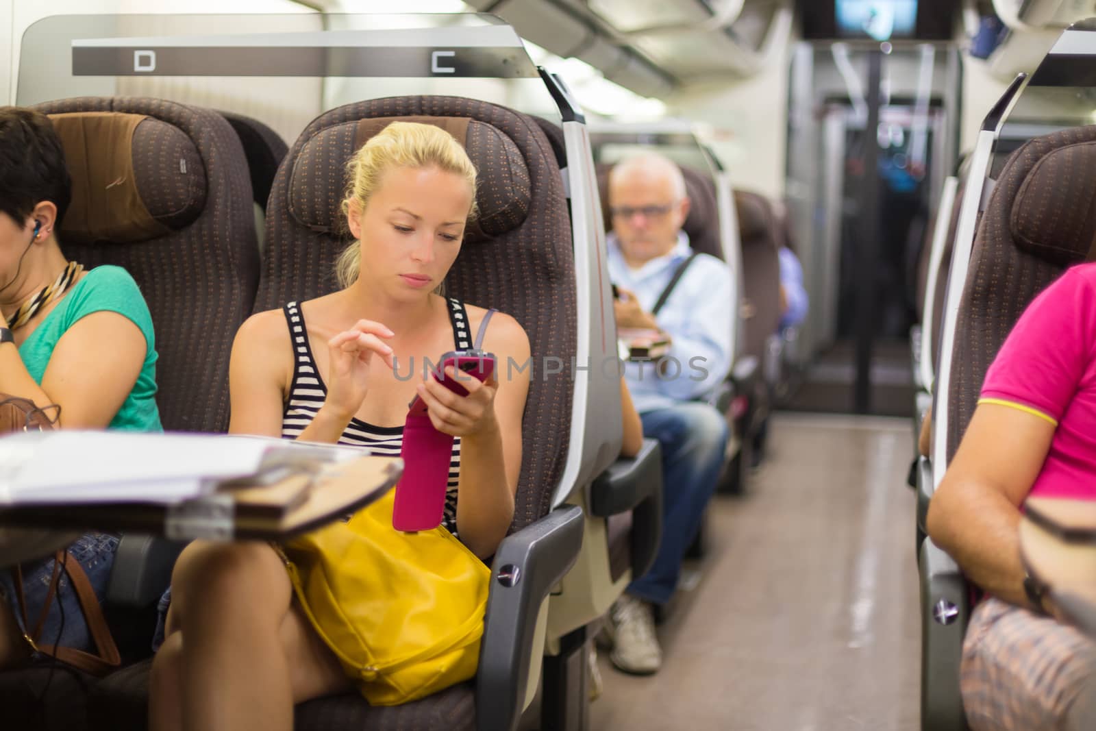 Thoughtful young lady surfing online on smartphone while traveling by train.