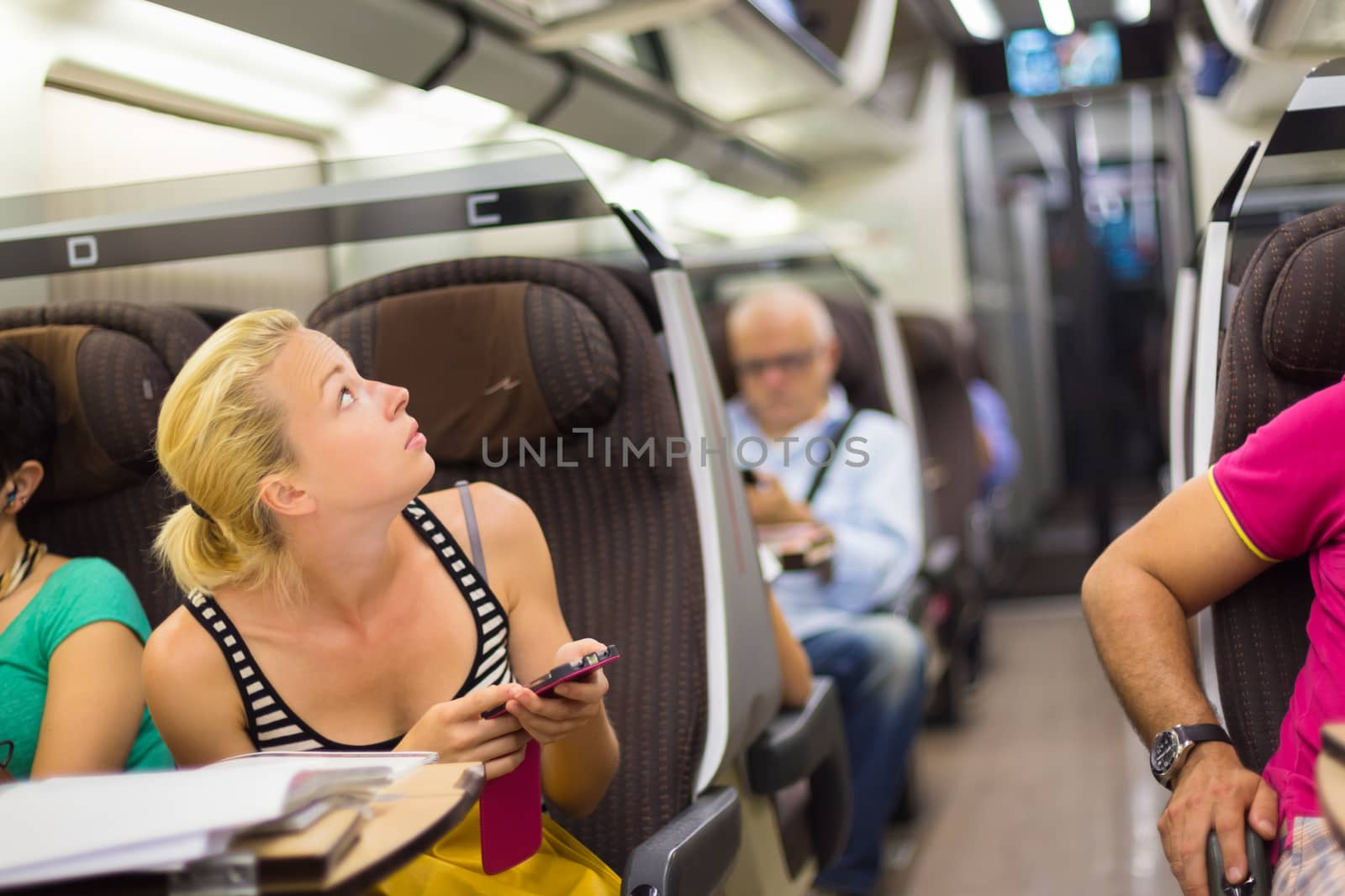 Thoughtful young lady surfing online on smartphone while traveling by train.