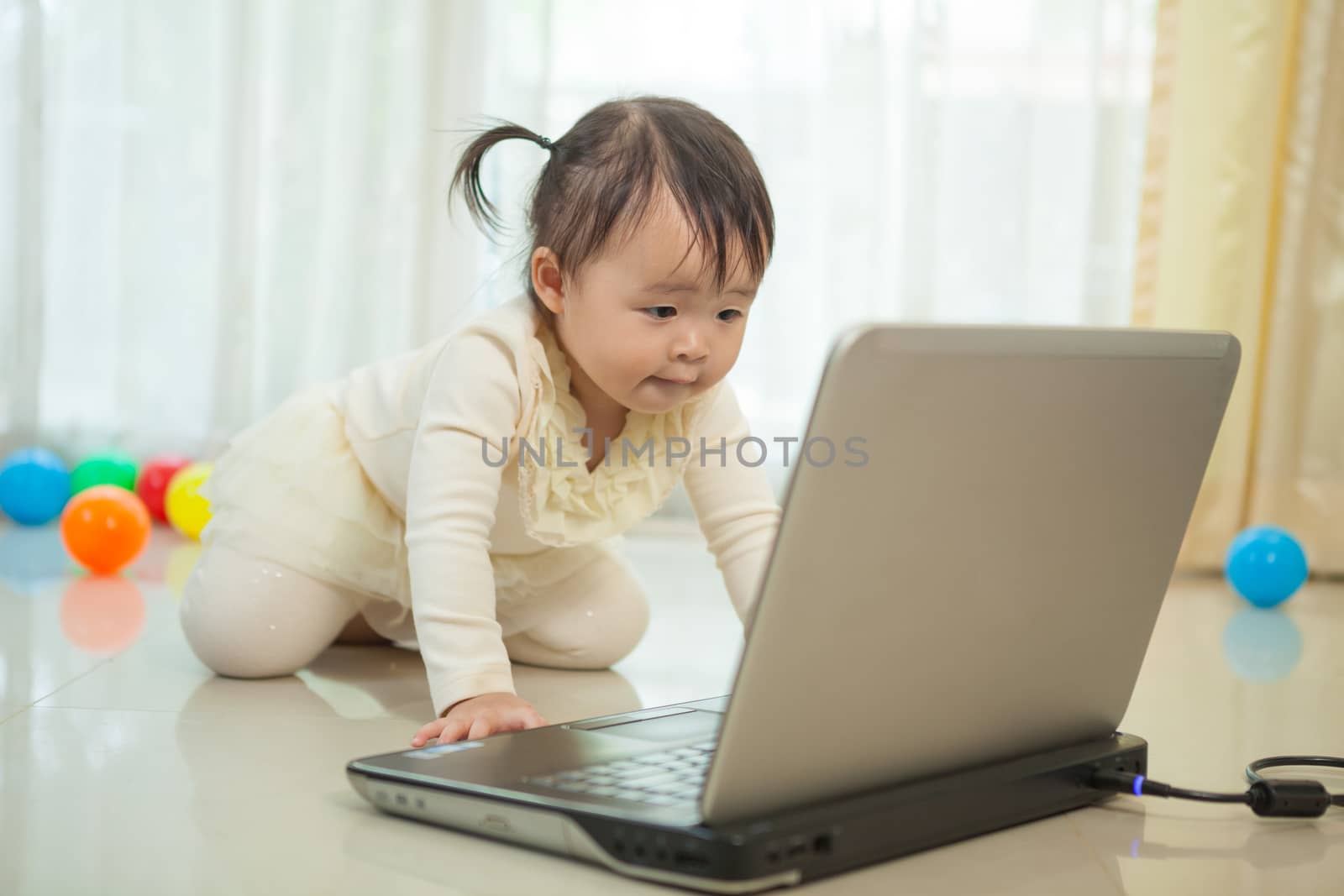 Little asian girl play laptop in home by witthaya