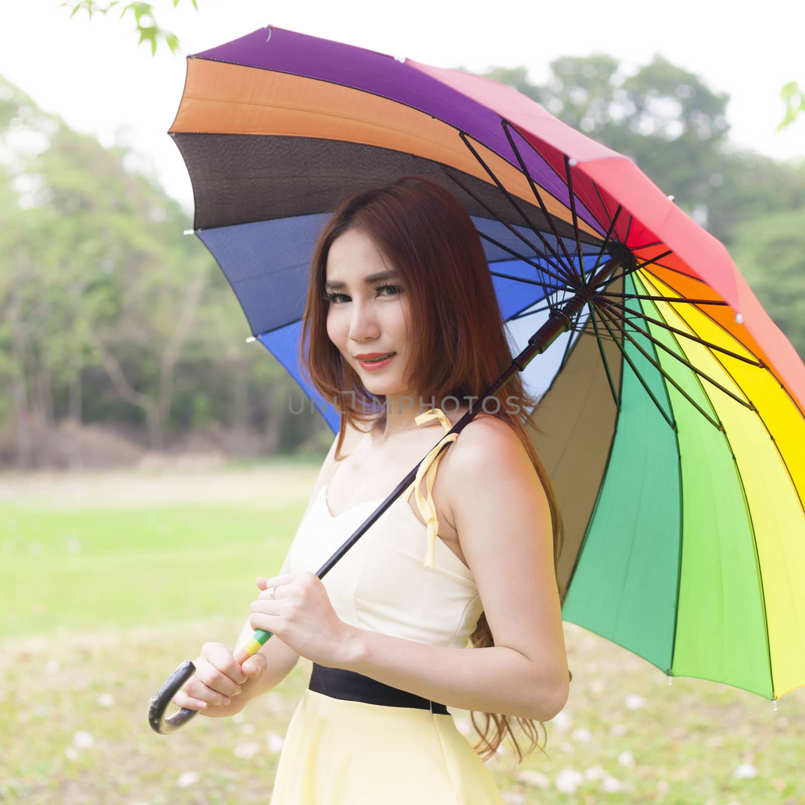 Woman holding multicolored umbrella On the grass in the park.