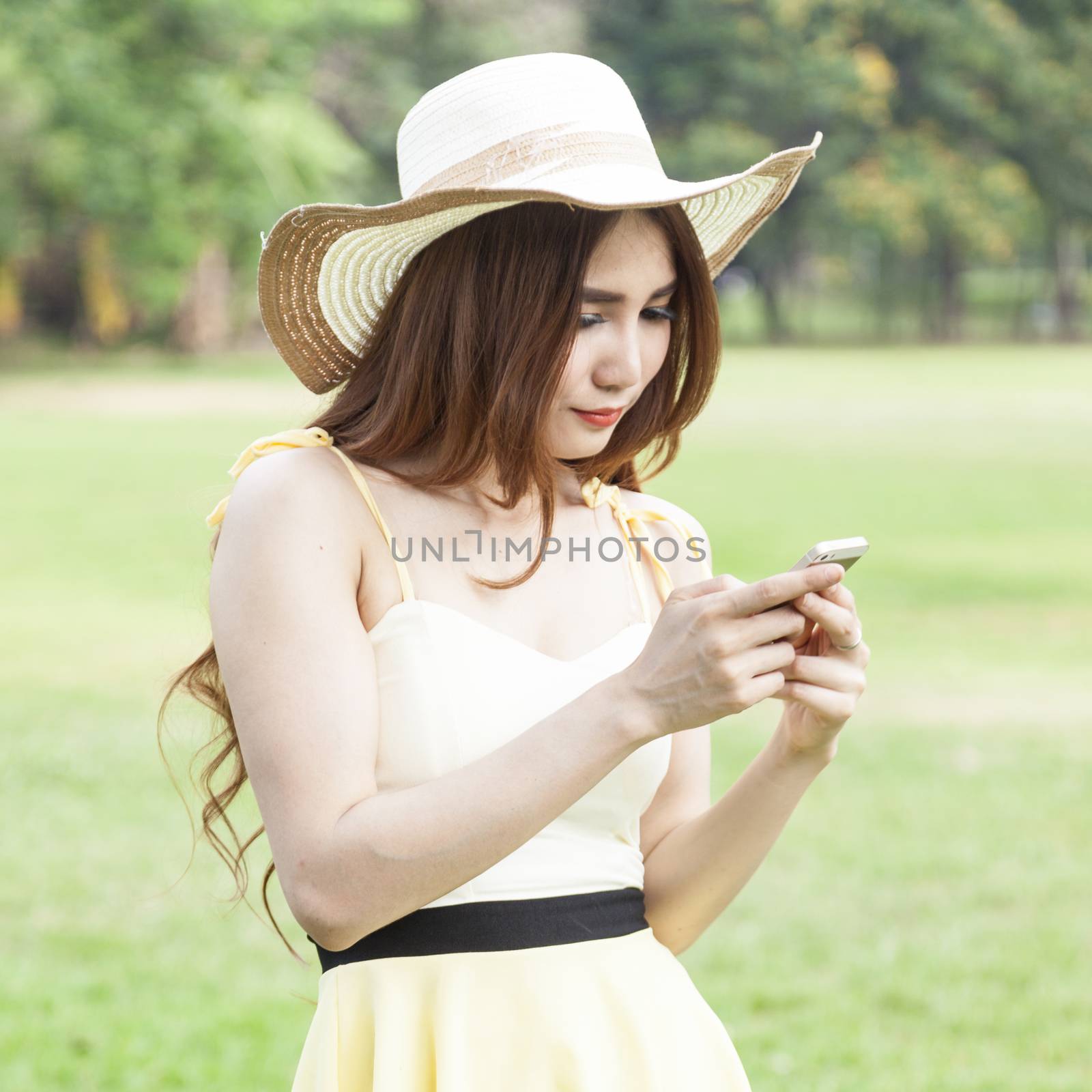Woman playing smart phone. While on the lawn in the park.