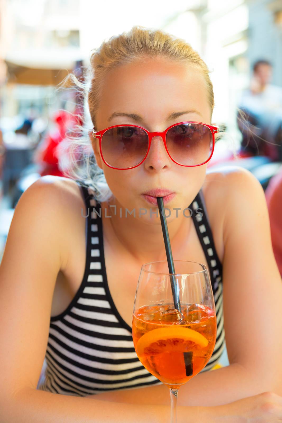 Woman terracing with aperol spritz cocktail in street cafe.