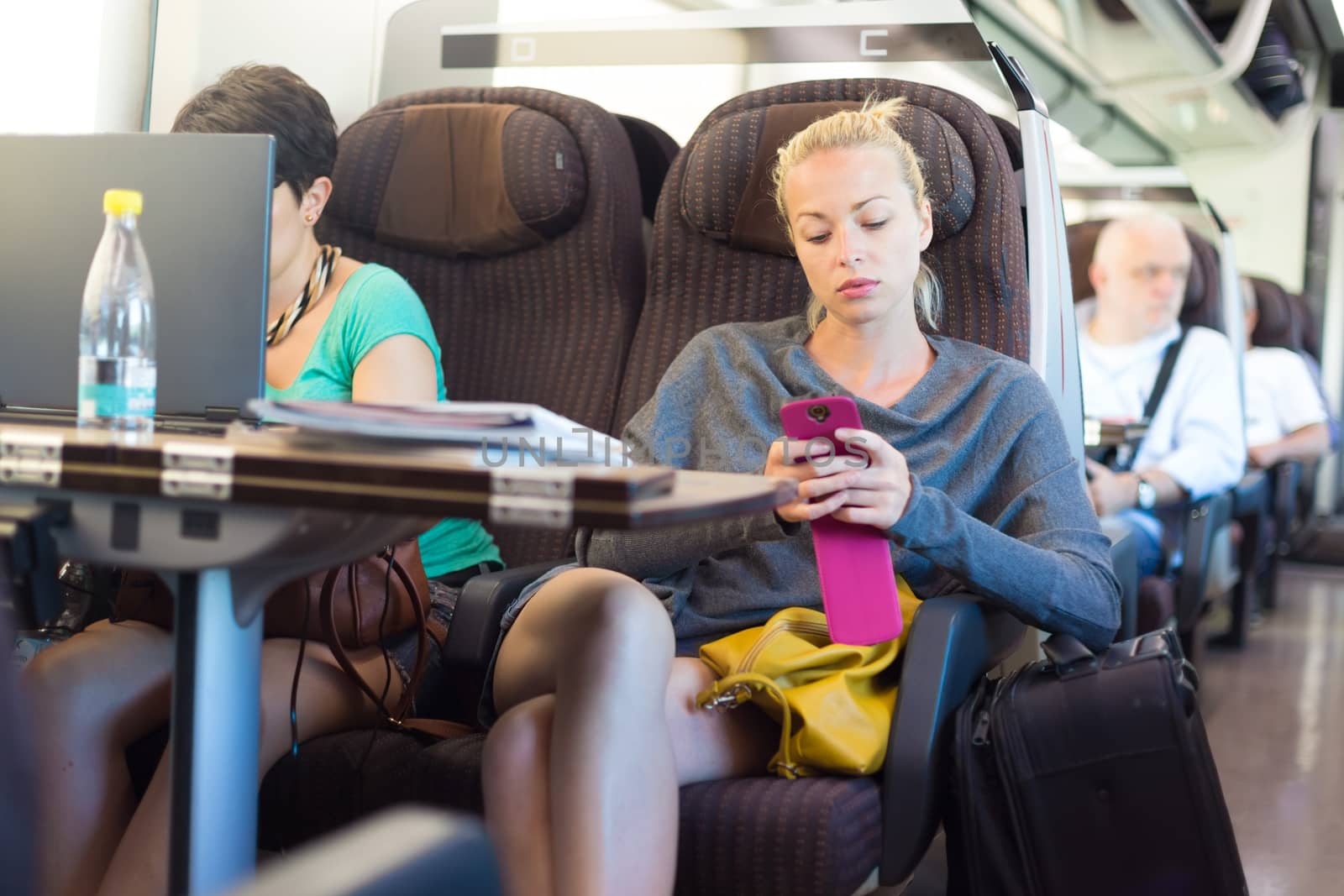 Thoughtful young lady surfing online on smartphone while traveling by train.
