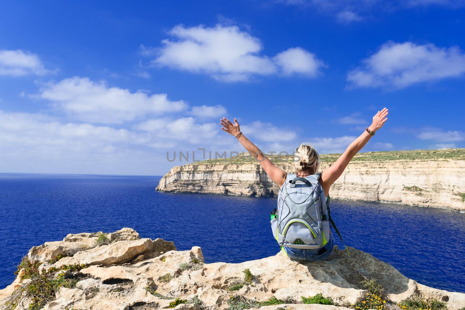 Woman looking at coast line near Azure Window on Gozo Island by Nanisimova