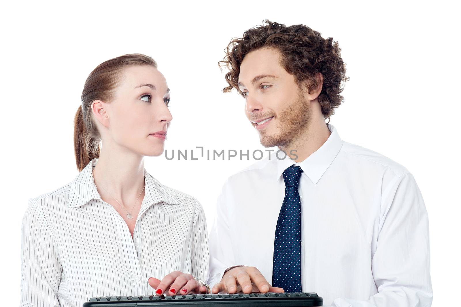 Two executives typing on keyboard, looking each others