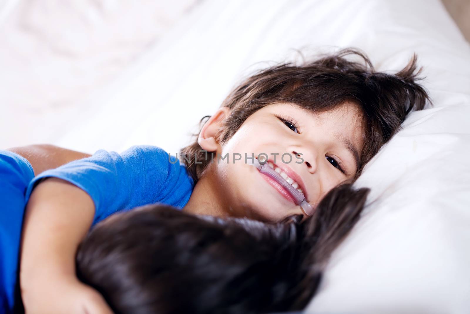 Disabled little boy hugging sister on bed