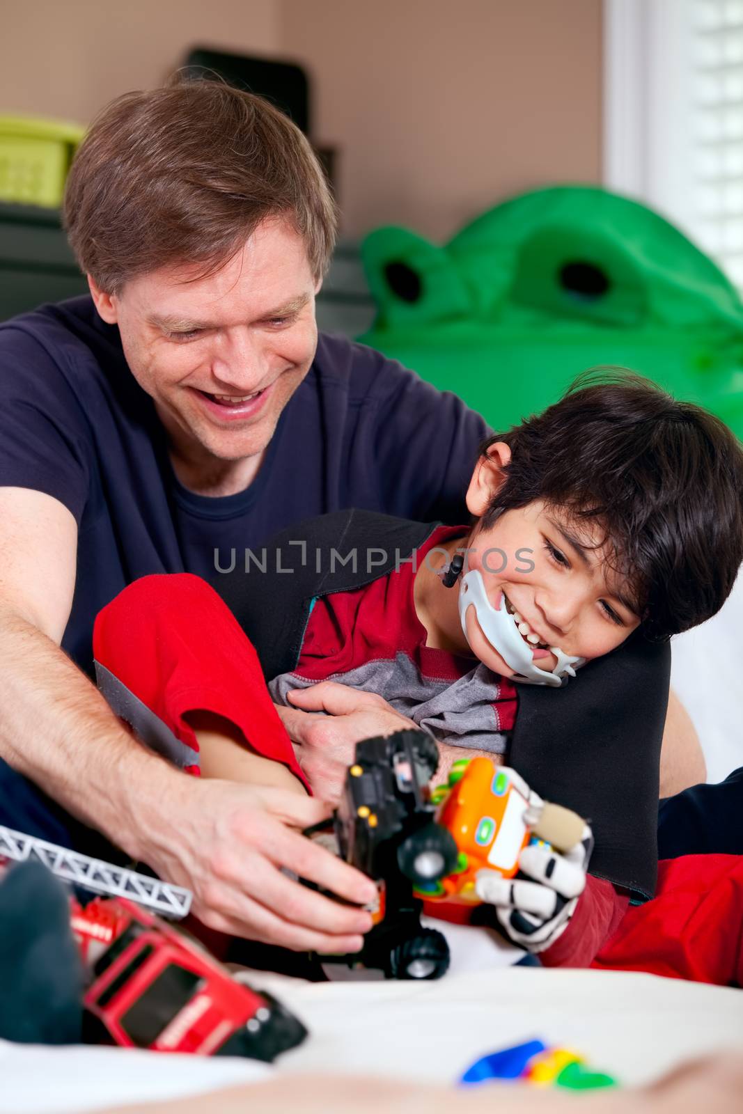 Handsome father playing cars with disabled son on floor mat