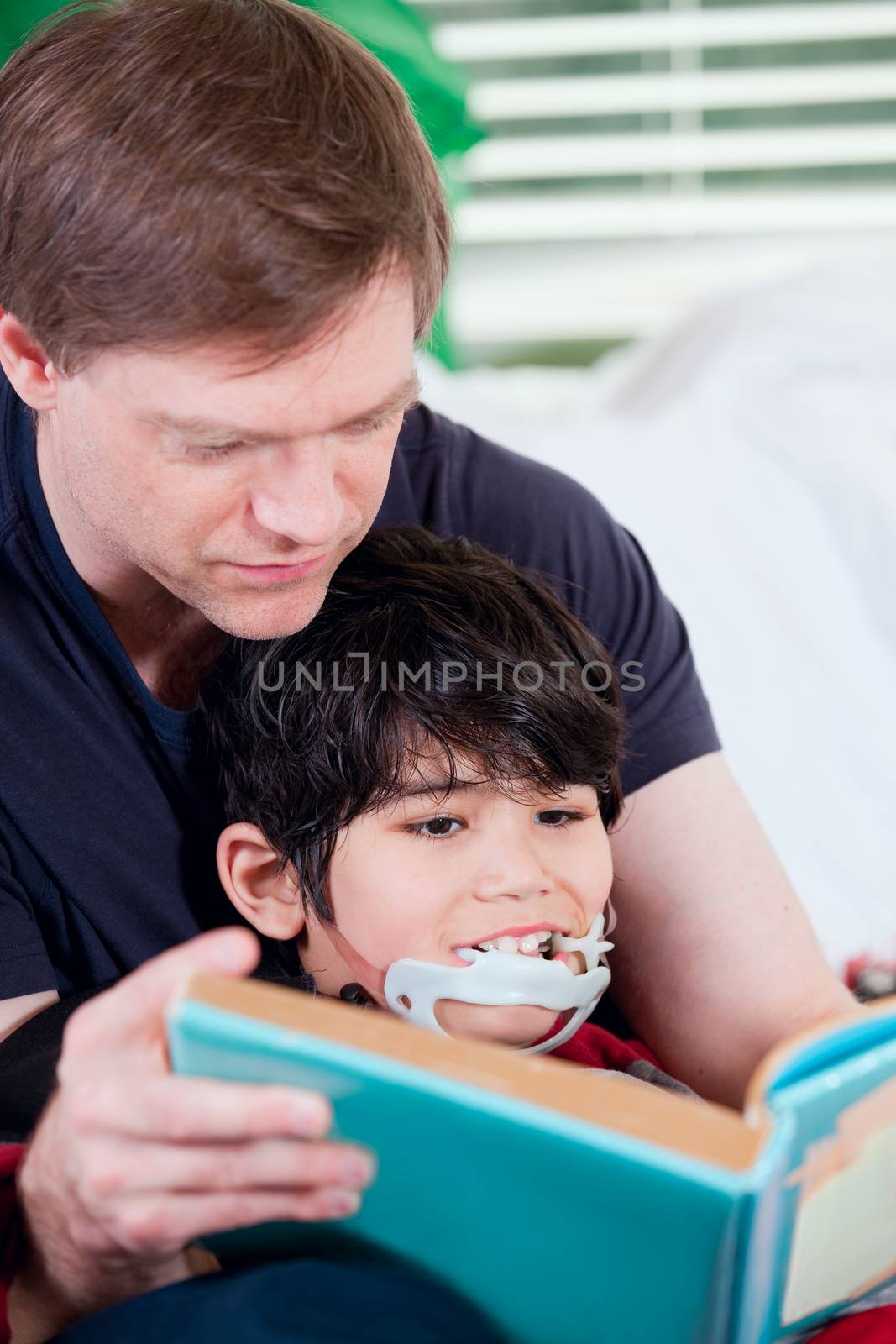 Father reading book to disabled little son by jarenwicklund