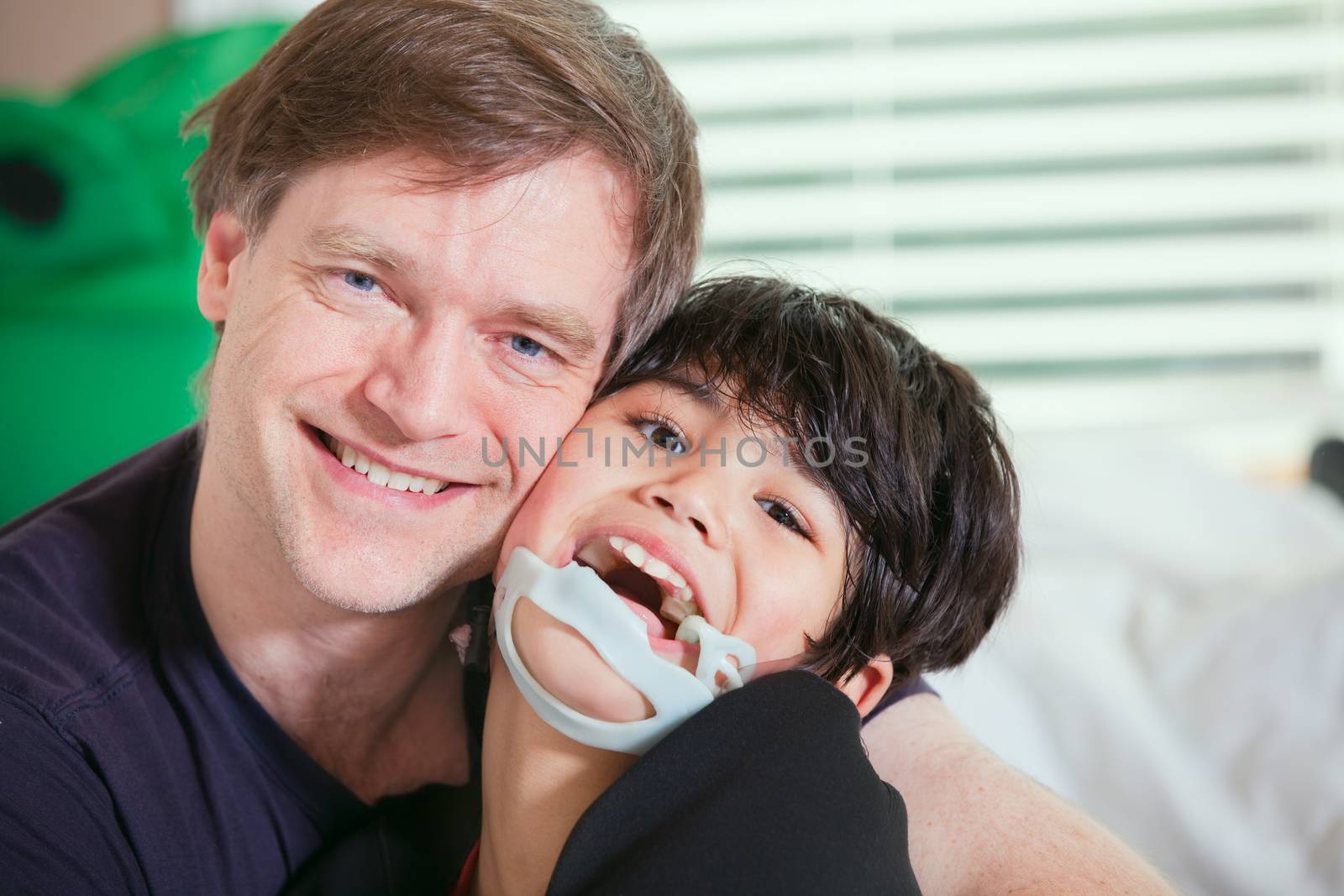 Smiling father holding disabled son by jarenwicklund