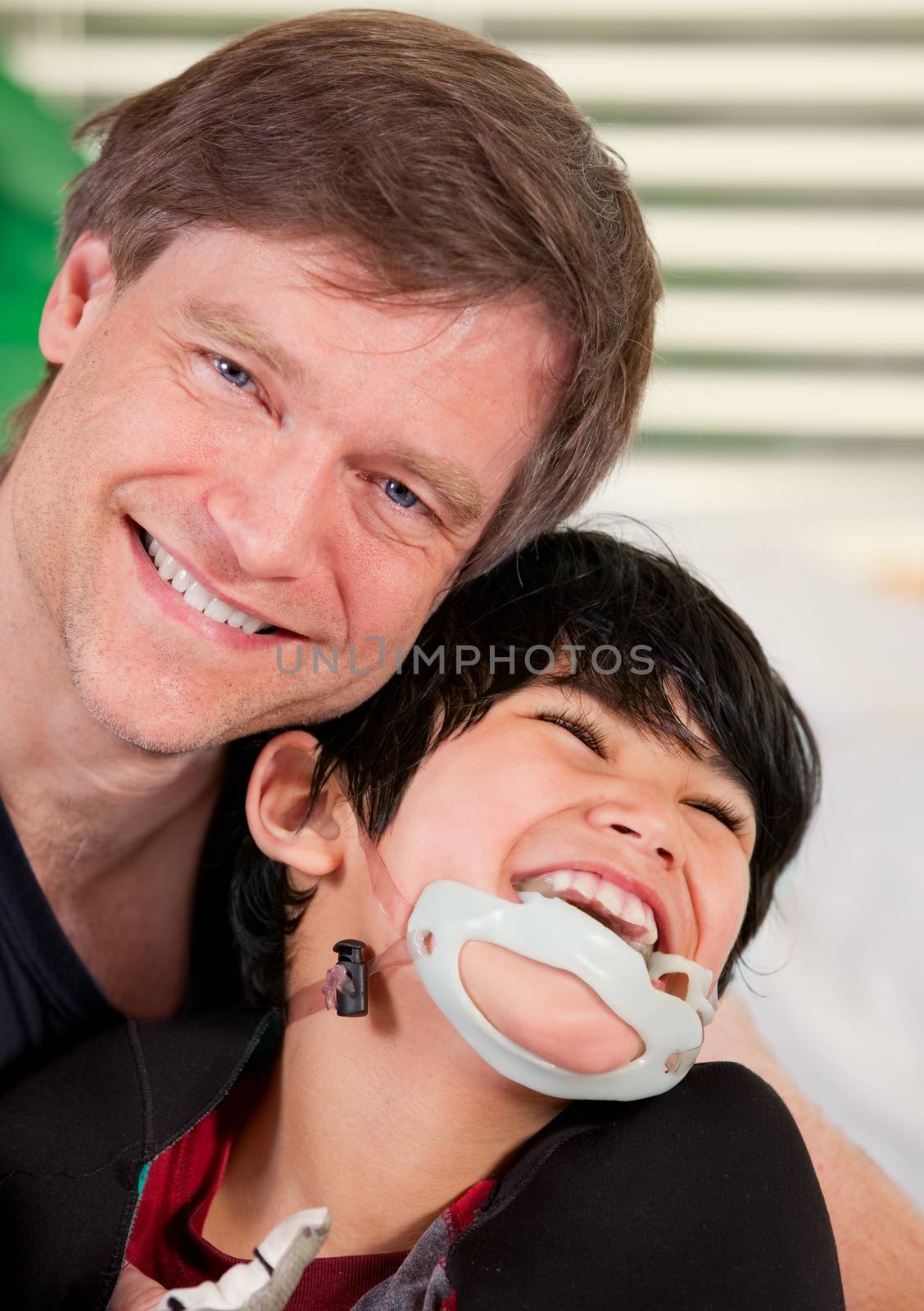 Smiling father holding disabled son by jarenwicklund