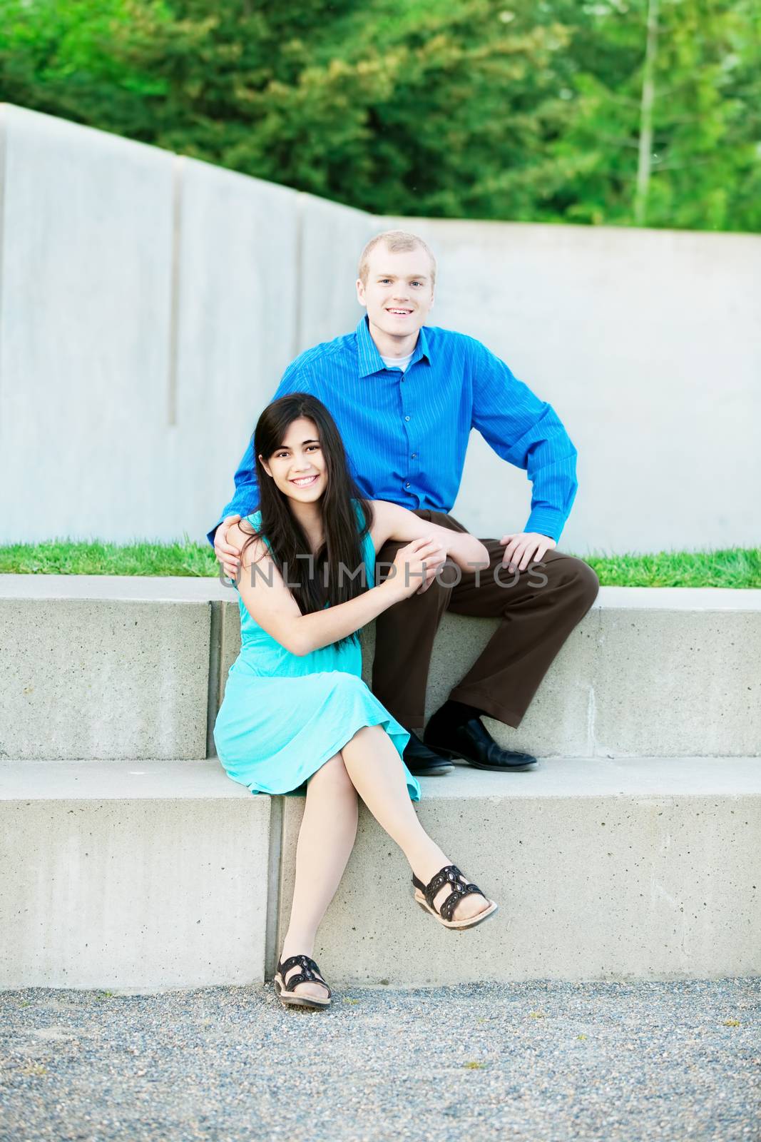 Happy interracial couple sitting together outdoors at park