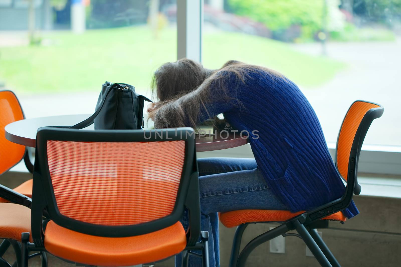Tired student asleep at school table, head on book