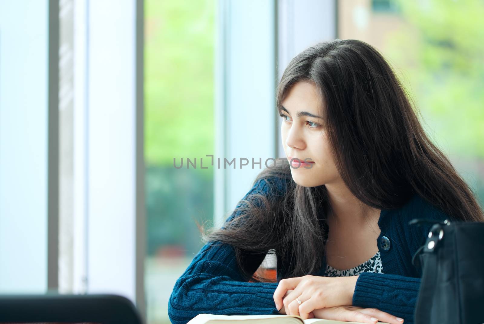 Young student looking out window while studying by jarenwicklund