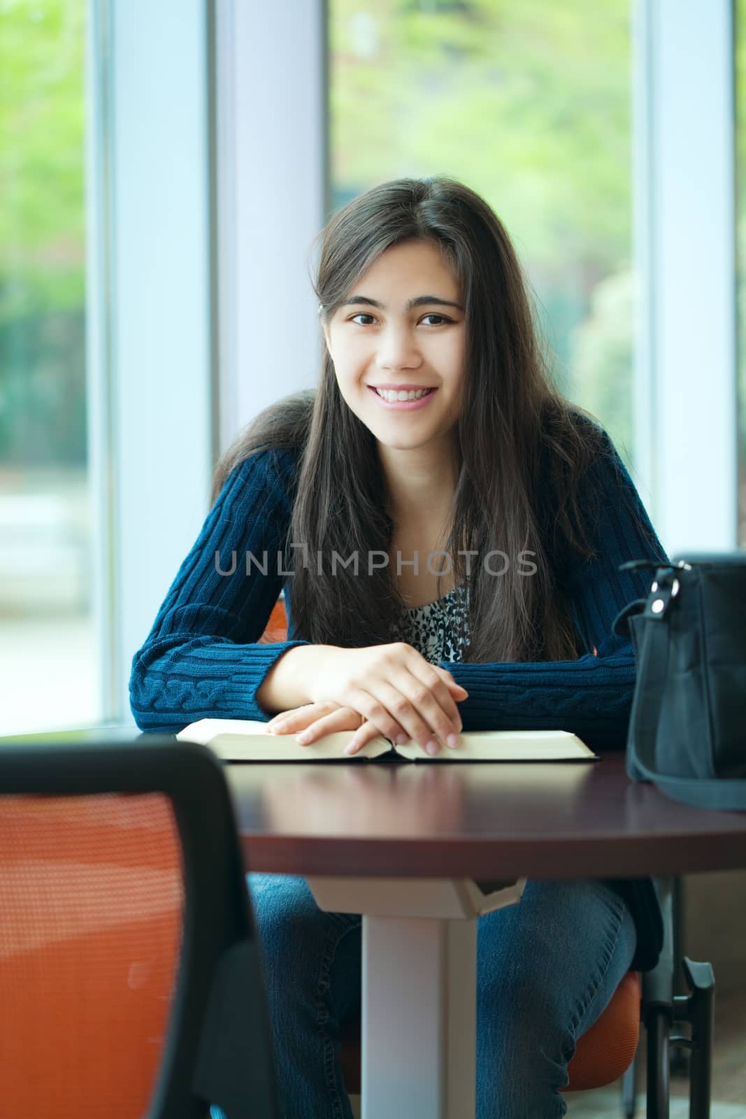 Happy young college student studying at school, book on table