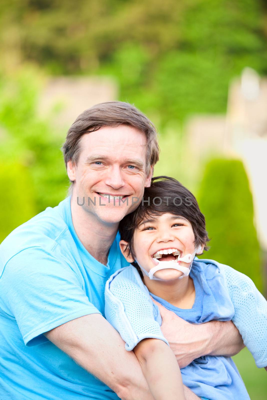 Handsome father holding smiling disabled son outdoors by jarenwicklund