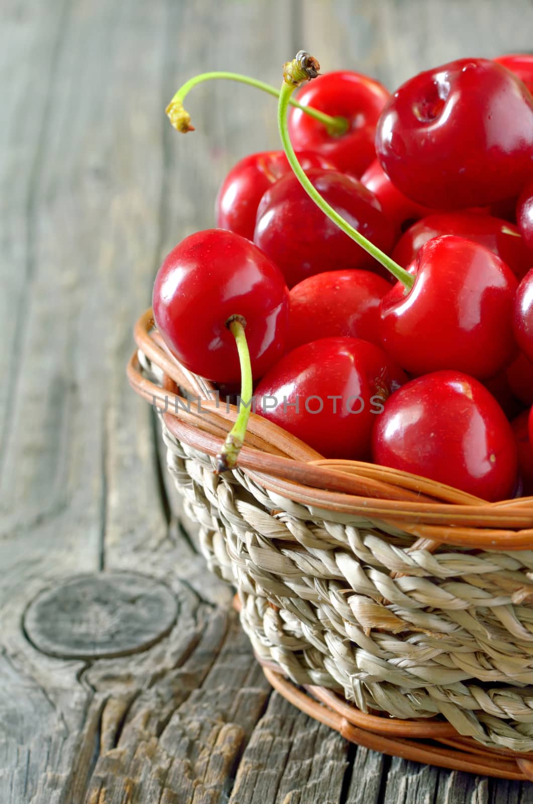 cherry in straw basket isolated on old wooden background