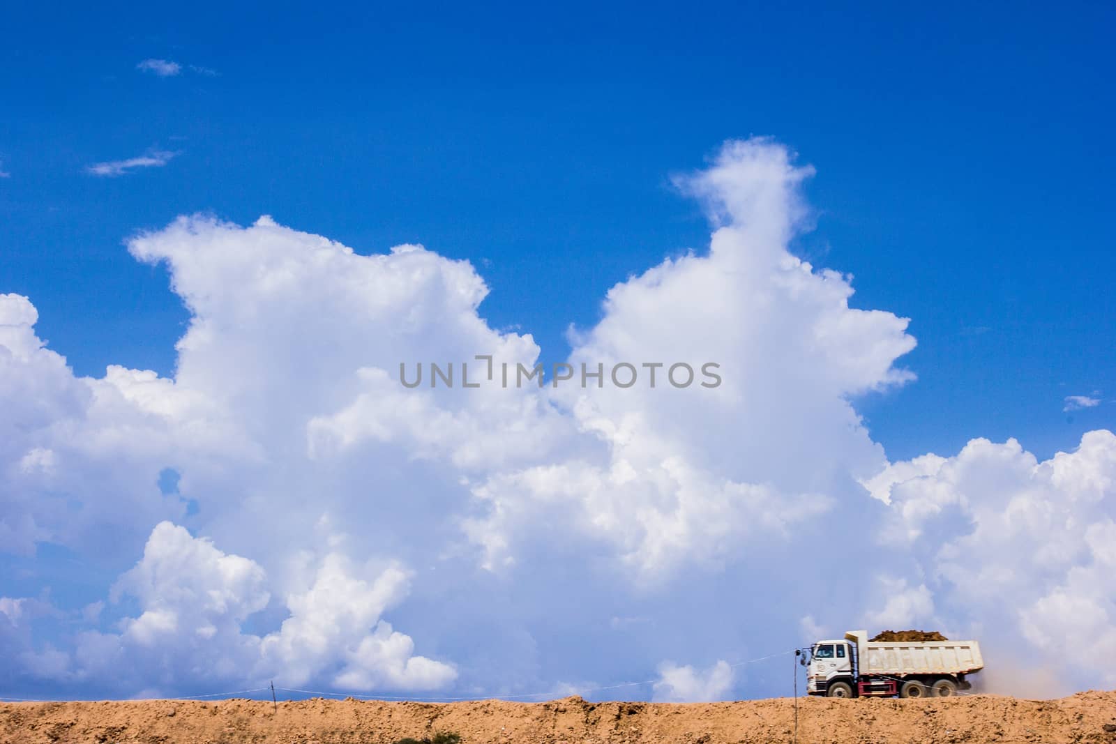 The truck running on sand soil, the sky as the background. by kannapon