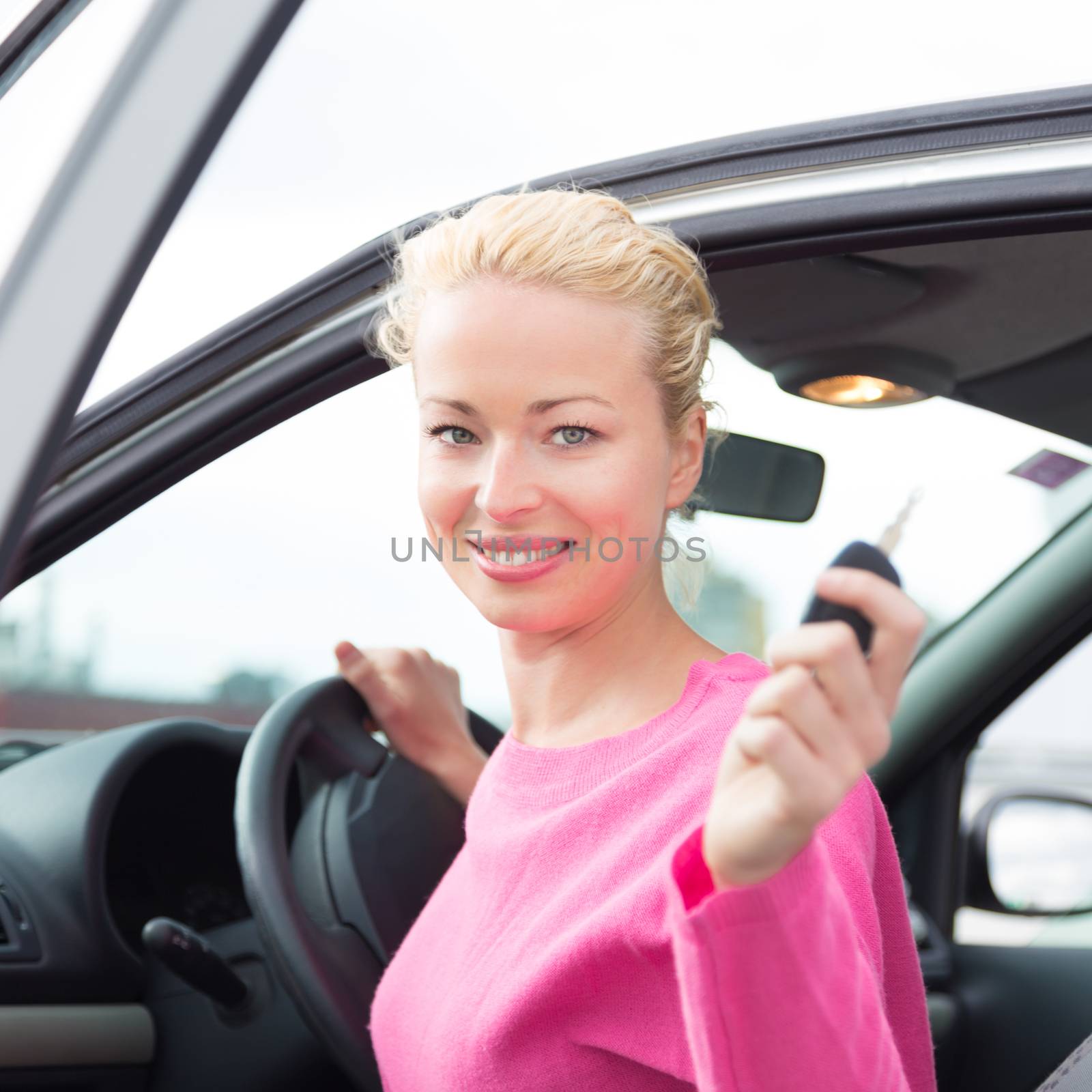 Woman driver showing car keys. Young female driving happy about her new car or drivers license. Caucasian model.