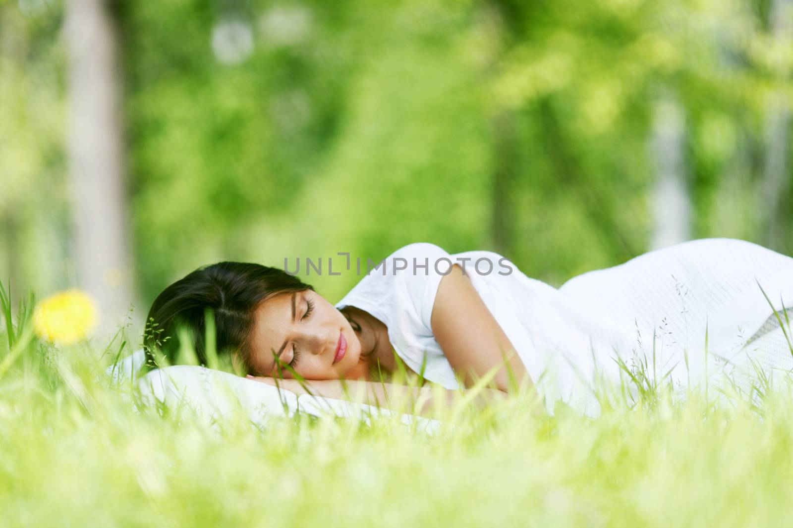 Beautiful young woman sleeping on grass outdoors