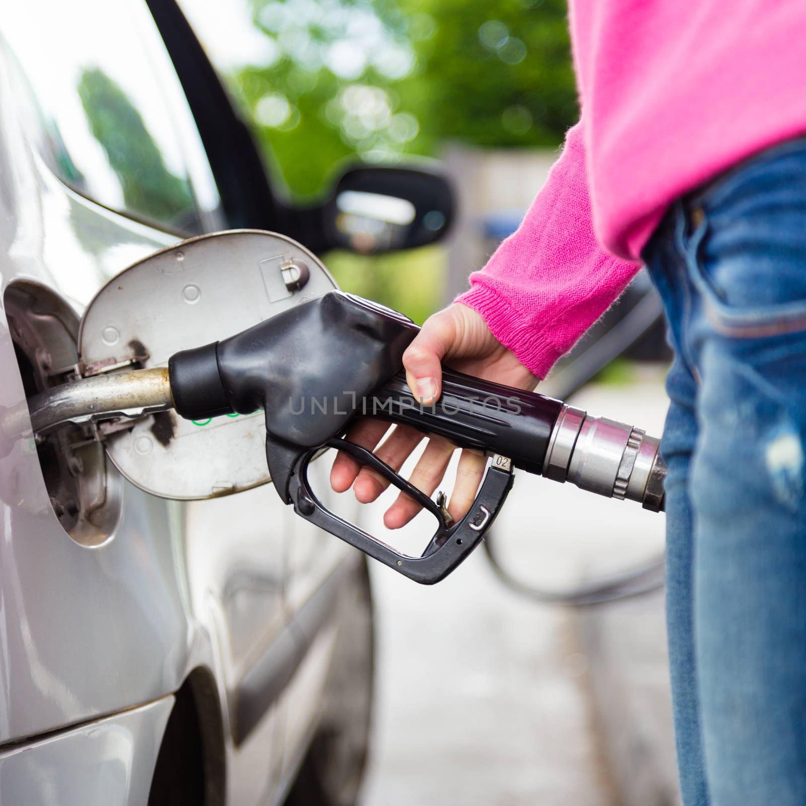 Closeup of woman pumping gasoline fuel in car at gas station. Petrol or gasoline being pumped into a motor vehicle car.