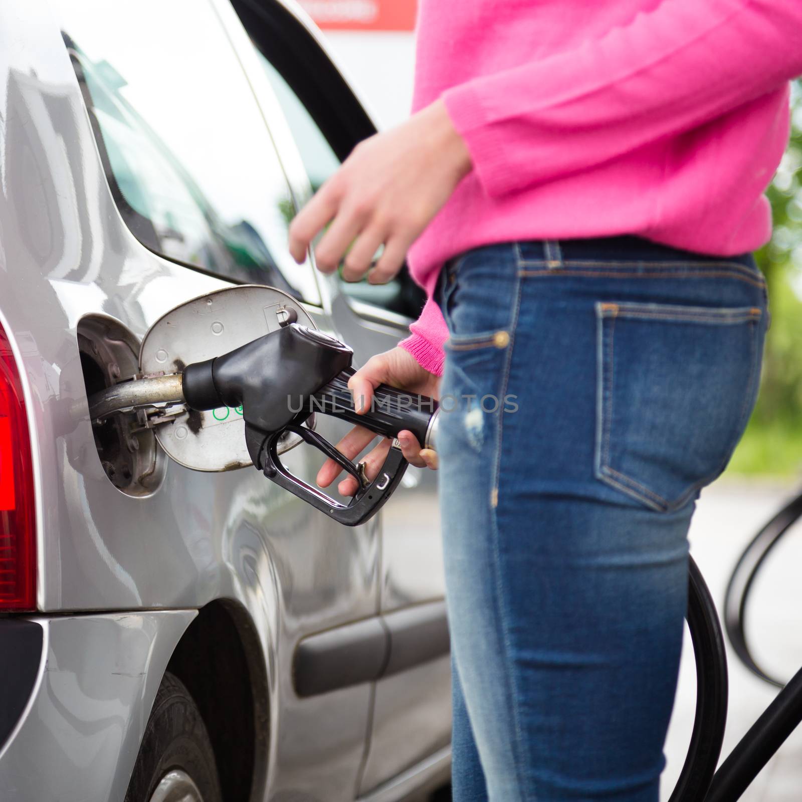 Closeup of woman pumping gasoline fuel in car at gas station. Petrol or gasoline being pumped into a motor vehicle car.