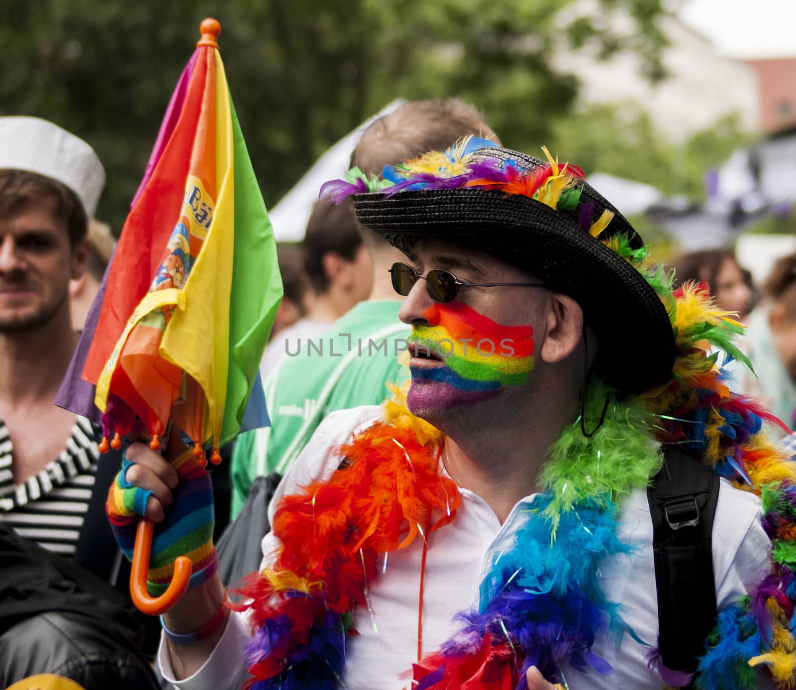 BERLIN, GERMANY - JUNE 21, 2014:Christopher Street Day.Crowd of people participate in the parade celebrates gays, lesbians, bisexuals and transgenders.Prominent in the image a elaborately dressed man with garlands and colorful umbrella.