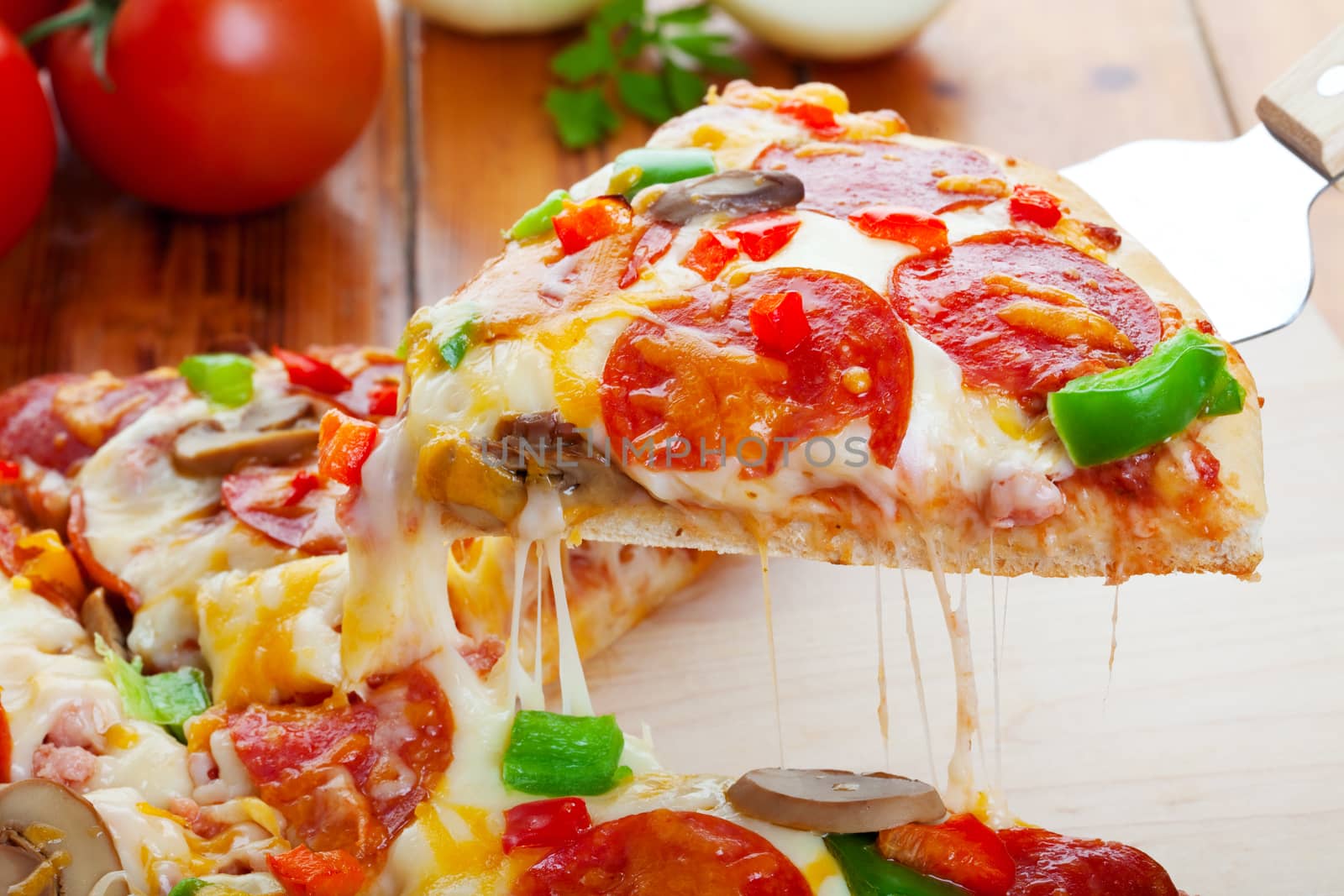 A slice of hot pizza deluxe with pepperoni, mushrooms, peppers, & lots of gooey mozzarella cheese, ready to be served.